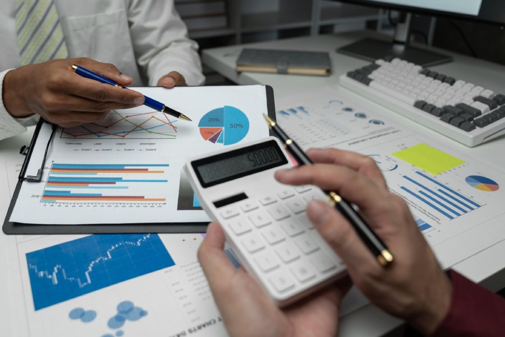 Persona señala una gráfica en un documento mientras otra usa una calculadora
